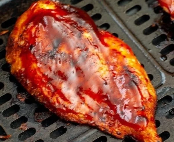 Juicy air fryer BBQ chicken breast served on a plate with garnish.