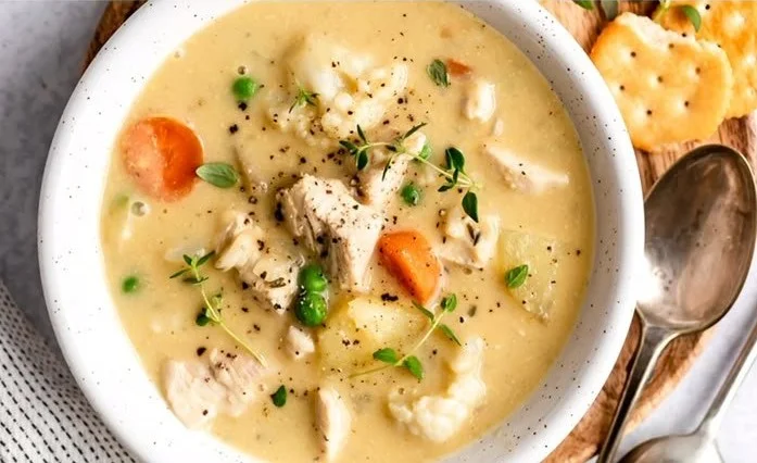 Cozy Chicken Pot Pie Soup in a bowl, topped with fresh herbs.