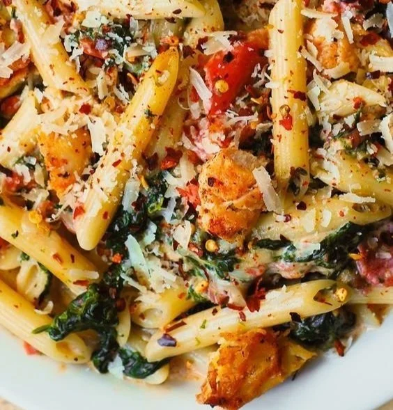 Creamy chicken pasta with spinach and tomatoes served in a bowl