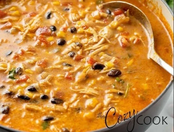 Creamy chicken tortilla soup served in a bowl with tortilla strips and fresh herbs