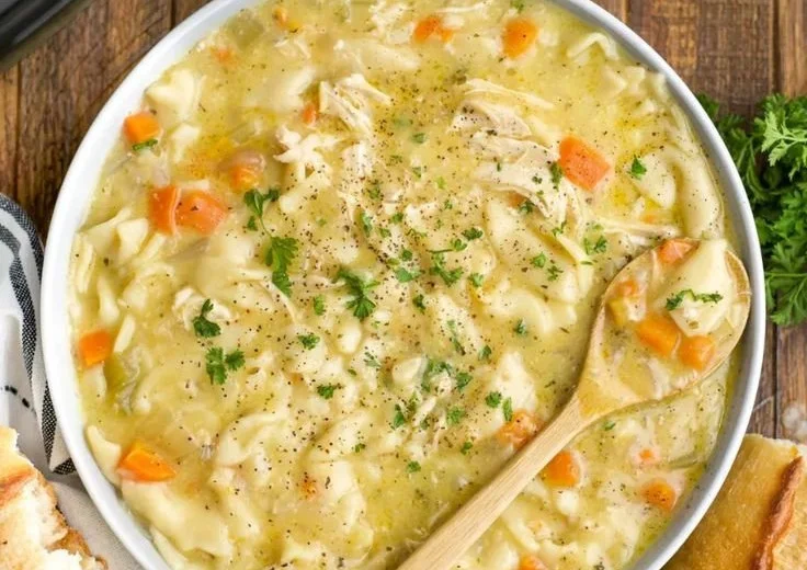 Bowl of easy crockpot creamy chicken noodle soup garnished with fresh herbs