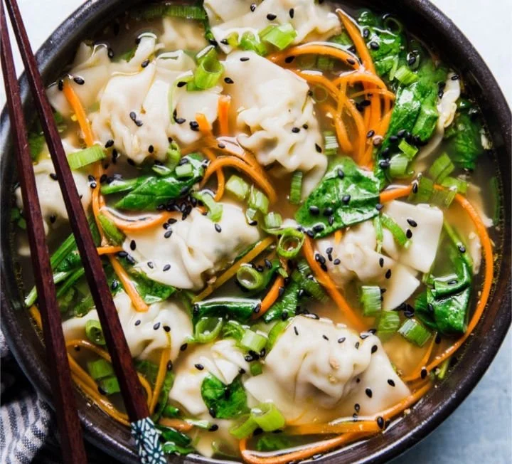 Bowl of easy dumpling soup with fresh herbs and vegetables