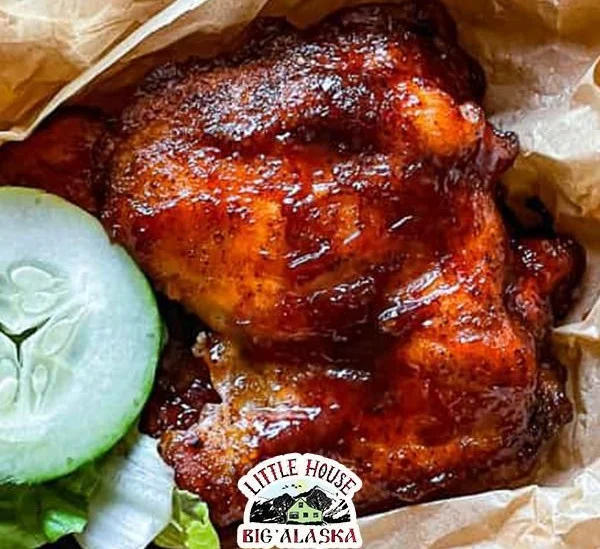 Plate of easy oven baked barbecue chicken with sauce and herbs.