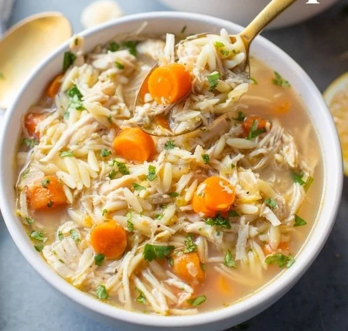 Bowl of Greek Lemon Chicken Soup garnished with fresh herbs and lemon slices.