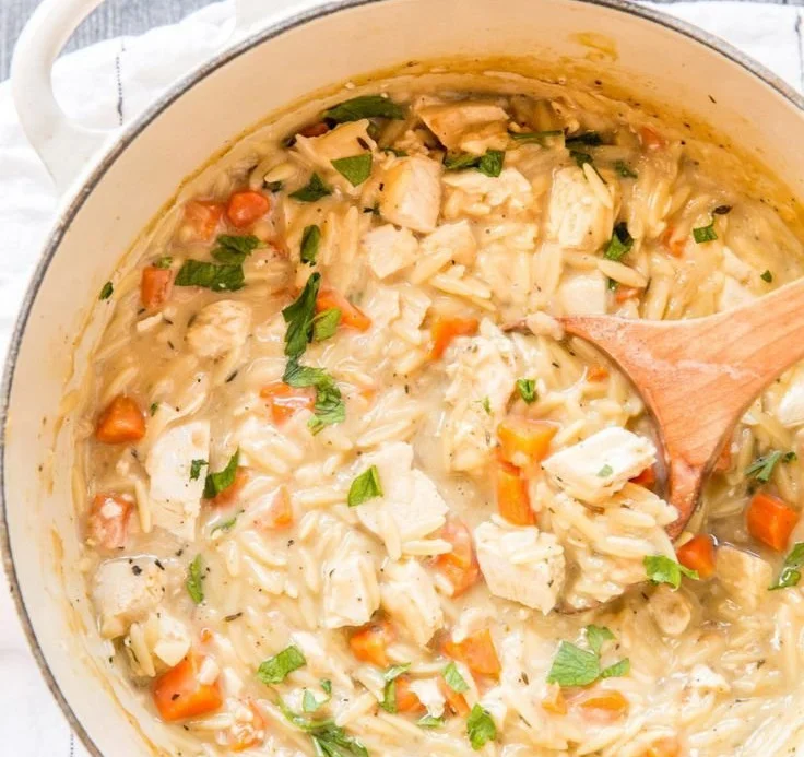 Rich and creamy chicken orzo soup in a bowl, garnished with herbs