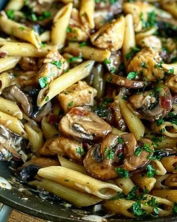 Creamy chicken mushroom pasta served in a bowl with herbs and parmesan cheese
