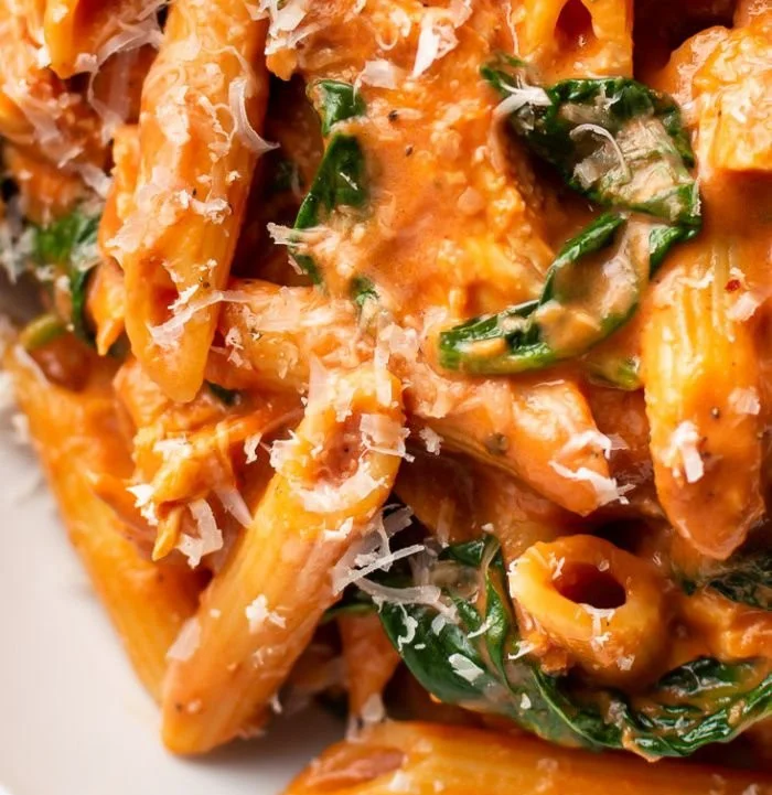 Delicious Tomato Spinach Chicken Pasta served in a bowl garnished with fresh herbs