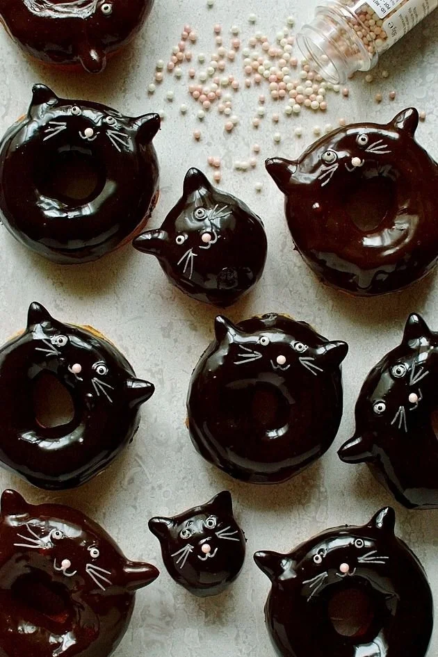 Delicious chocolate glazed black cat doughnuts shaped like playful kittens.