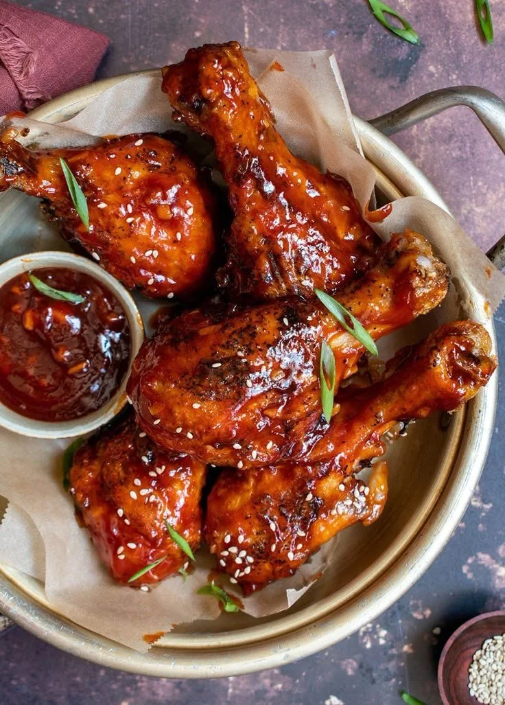 Plate of crispy spicy Korean fried chicken garnished with sesame seeds and green onions.