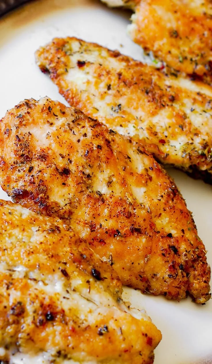 Juicy pan-seared chicken breasts on a plate with herbs