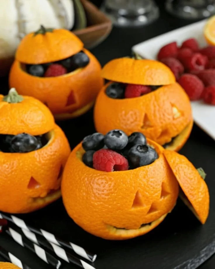 Halloween brunch party food featuring pumpkin-shaped fruit and orange dishes.