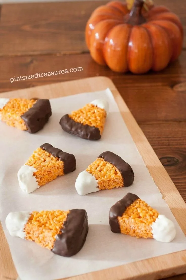 Cute Halloween sweets like ghost cookies and pumpkin cupcakes on a festive table.