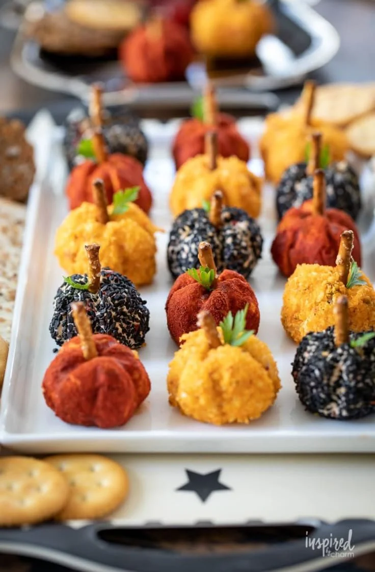 Halloween appetizers featuring mini pumpkins and gourmet crackers on a festive platter.